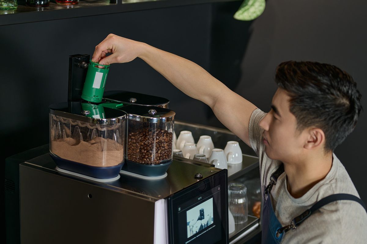 Barista füllt den Reinigerbehälter einer professionellen WMF Kaffeemaschine