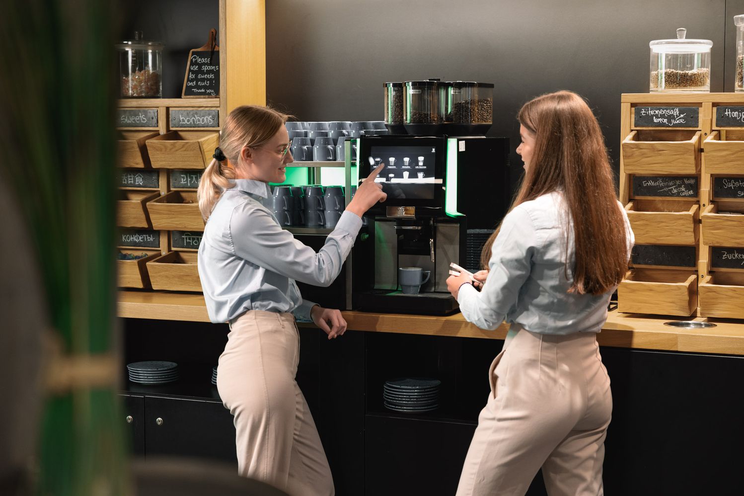 Two women using a WMF coffee machine at Linder hotel